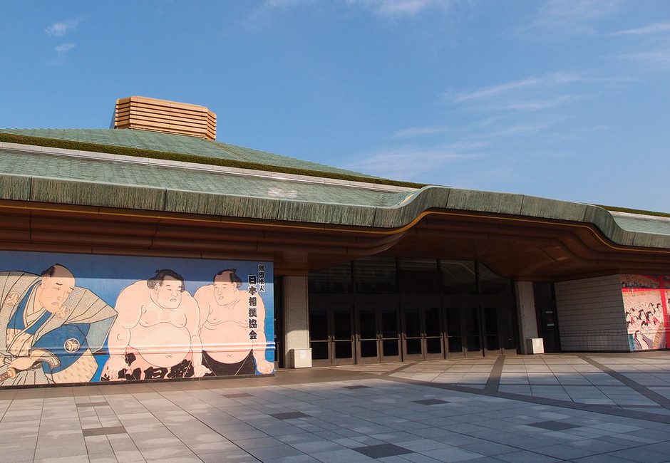 The green-roofed entrance of Ryogoku Kokugikan with its painted sumo wrestler murals