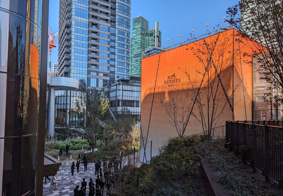 Planted walkways and orange-clad pavilion among the towers of Azabudai Hills on opening day