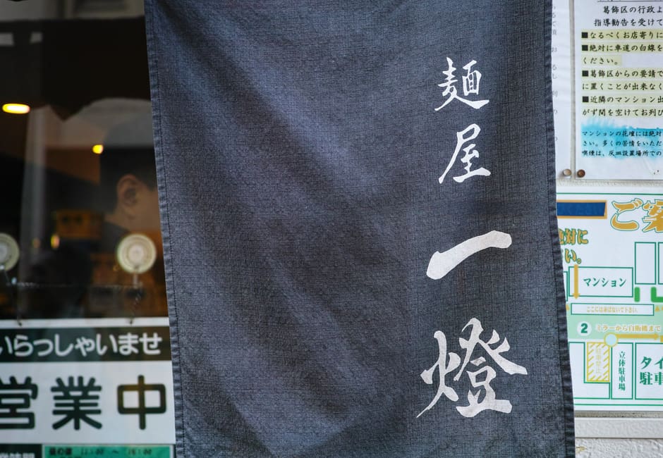 Navy noren curtain printed with the Menya Itto name at the ramen shop entrance in Shin-Koiwa