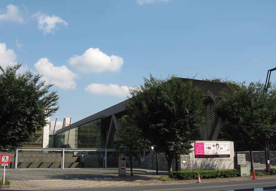 Long low facade of the Museum of Contemporary Art Tokyo behind trees in Kiba Park, Kiyosumi