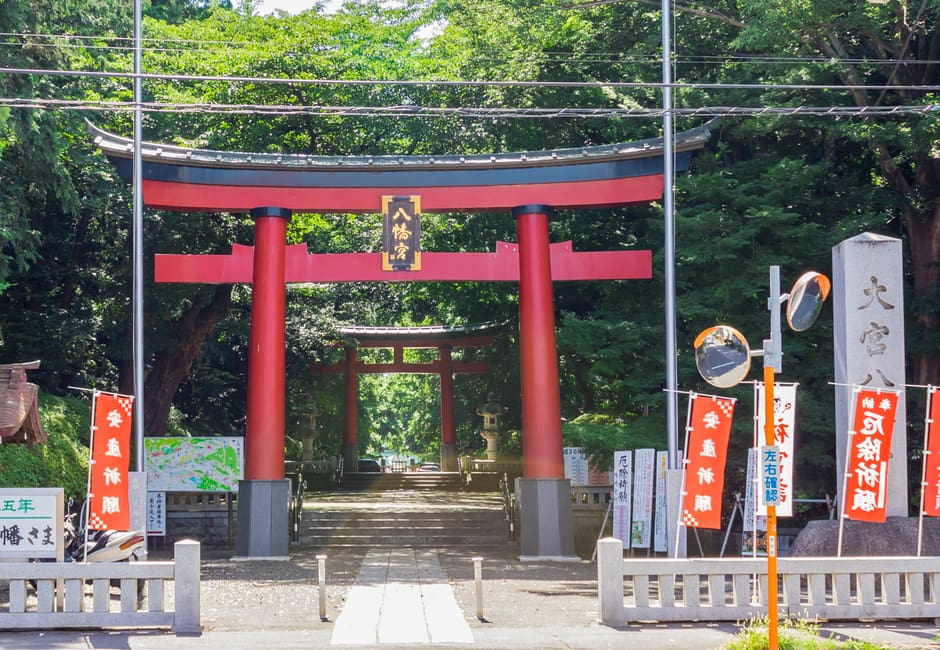 The vermilion torii at the entrance of Omiya Hachimangu Shrine in Suginami, with trees behind