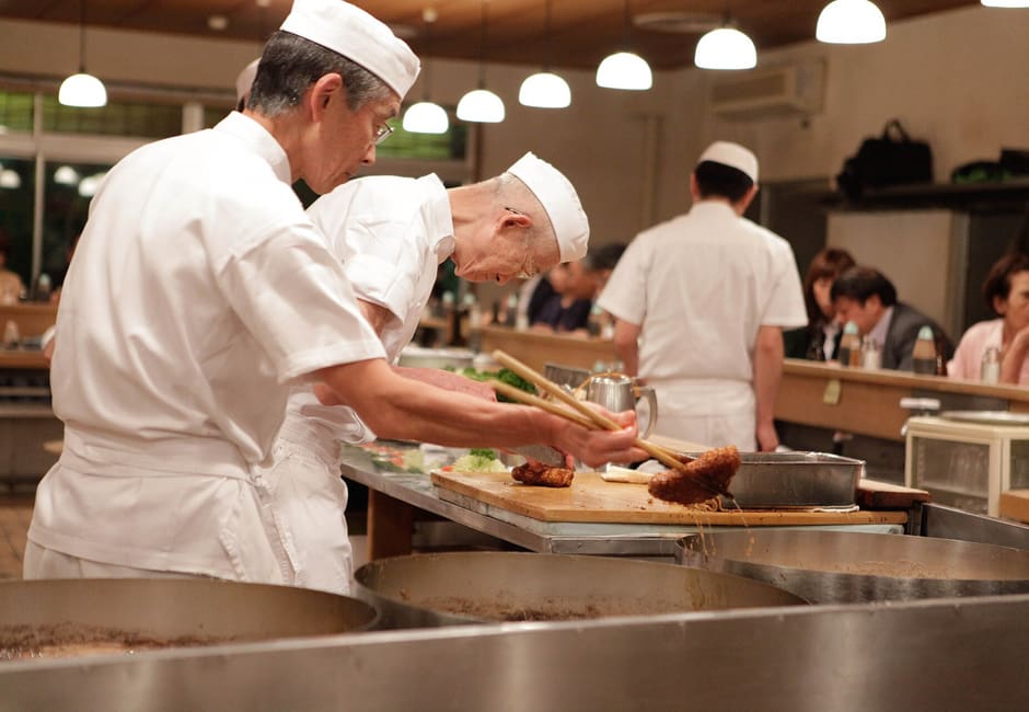 White-clad cooks frying tonkatsu behind the long wooden counter at Tonki in Meguro