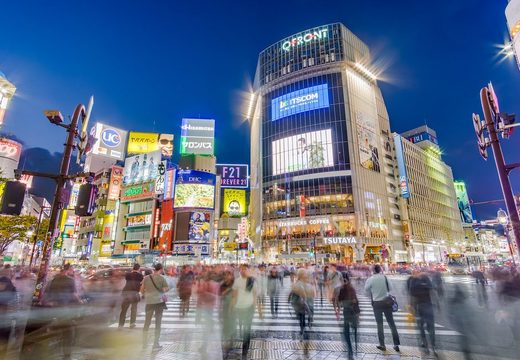 Crowds crossing the Shibuya Scramble at blue hour beneath the QFront screens