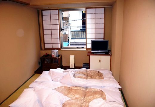 Futons laid out on tatami under shoji windows in a small ryokan room in Asakusa, Tokyo