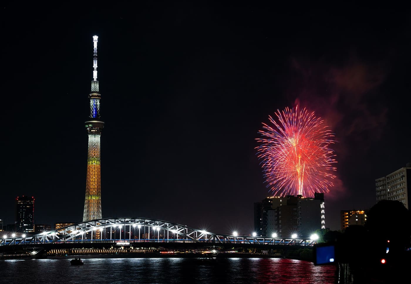 Fireworks bursting beside Tokyo Skytree above Azumabashi Bridge on the Sumida River