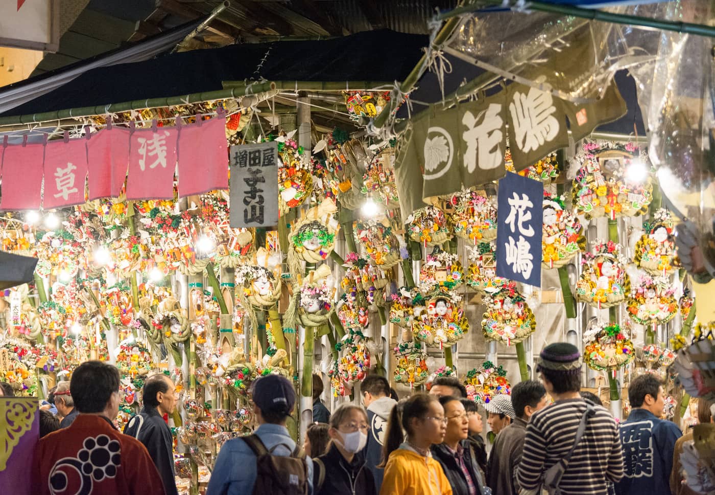 Crowds at a kumade stall hung with lucky bamboo rakes at the Tori-no-ichi fair