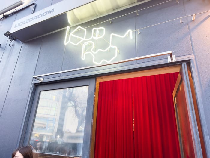 Neon LIQUIDROOM logo above the red-curtained entrance of the Ebisu live house