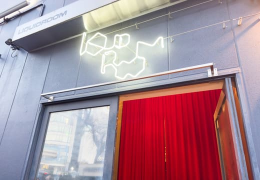 Neon LIQUIDROOM logo above the red-curtained entrance of the Ebisu live house