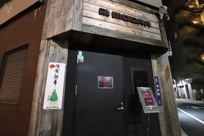 Wood-clad entrance and MOGRA sign of the Akihabara club on a back street at night