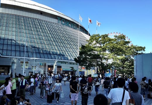 Tokyo Dome's curved glass facade and lettering above the approach at Suidobashi